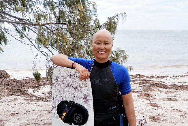 breast cancer survivor smiling with a surfing board