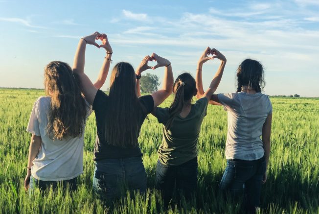 group of women forming hand-heart shape together